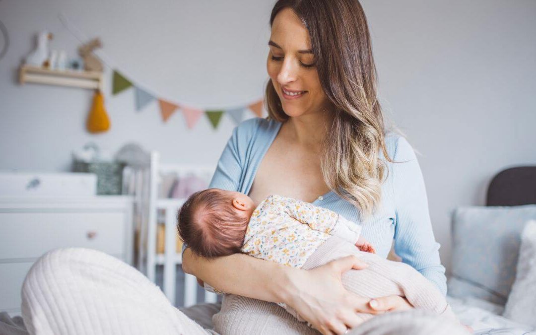 A mother is breastfeeding her baby in a cozy, decorated room.